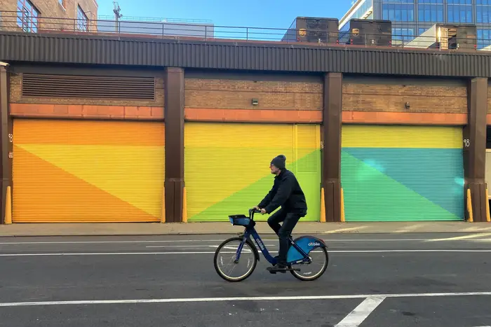a Citi Bike rider goes by a colorful warehouse